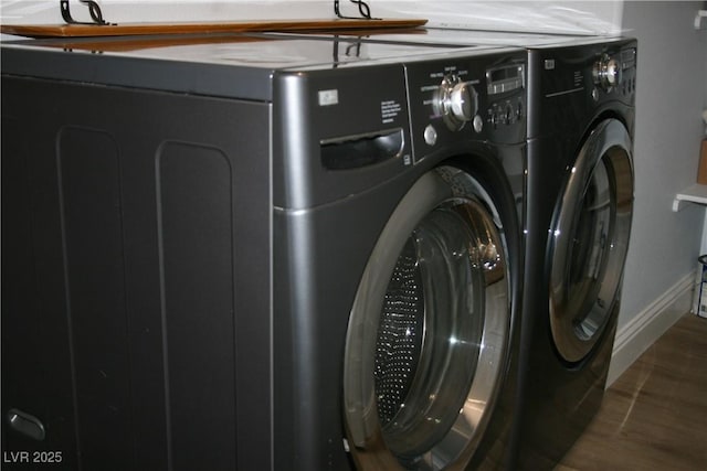 washroom with laundry area, baseboards, washer and clothes dryer, and wood finished floors