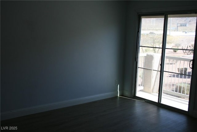 empty room with baseboards and dark wood-type flooring