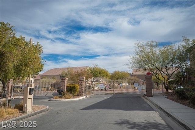 view of street with sidewalks, a gate, a gated entry, and curbs