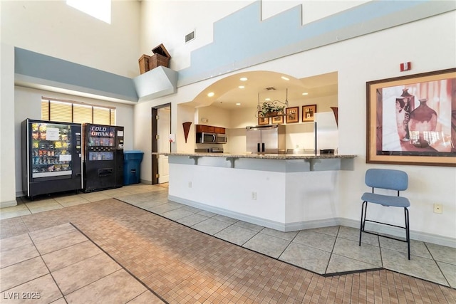 kitchen featuring light tile patterned floors, visible vents, appliances with stainless steel finishes, a peninsula, and a kitchen bar