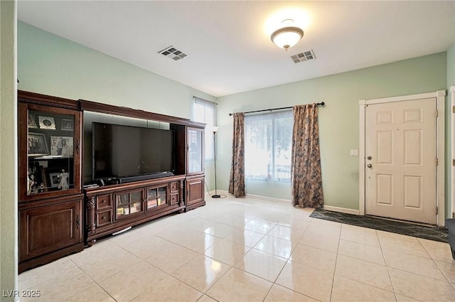 living room with light tile patterned floors, visible vents, and baseboards