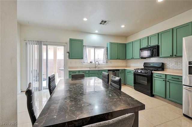 kitchen featuring green cabinets, a sink, visible vents, and black appliances