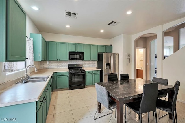 kitchen with a sink, black appliances, visible vents, and green cabinetry