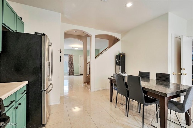 dining area featuring arched walkways, light tile patterned floors, recessed lighting, baseboards, and stairway