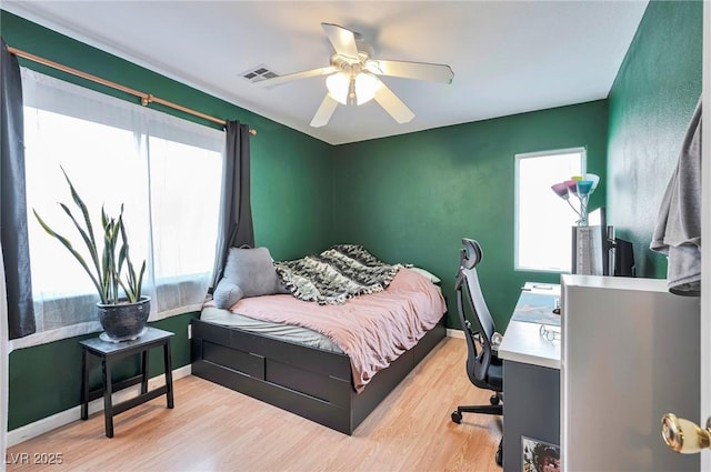 bedroom featuring multiple windows, wood finished floors, a ceiling fan, and baseboards