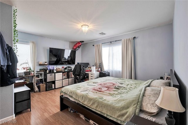 bedroom with light wood-type flooring, multiple windows, and visible vents