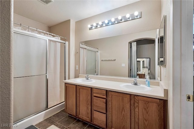 full bath featuring a stall shower, tile patterned flooring, a sink, and double vanity