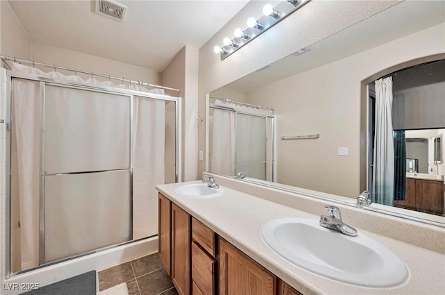 bathroom with double vanity, a stall shower, a sink, and visible vents