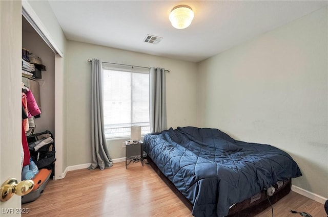 bedroom featuring a closet, light wood-type flooring, visible vents, and baseboards