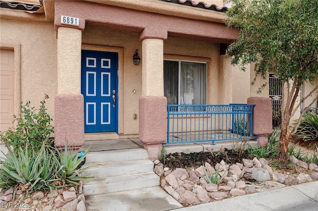 entrance to property featuring a porch and stucco siding