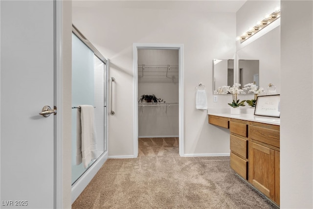 full bathroom featuring baseboards, vanity, a spacious closet, and a shower stall