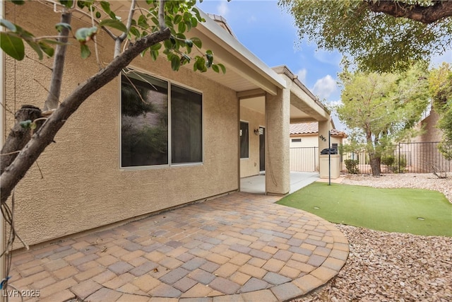 rear view of house with a patio area, stucco siding, and fence