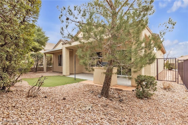 rear view of house with a patio area, stucco siding, a gate, and fence