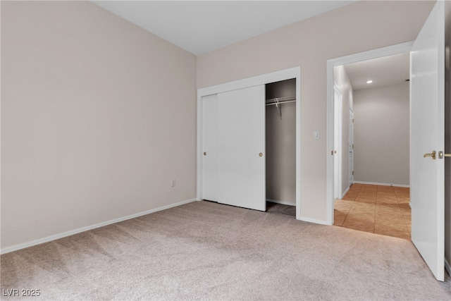 unfurnished bedroom with a closet, tile patterned flooring, baseboards, and carpet