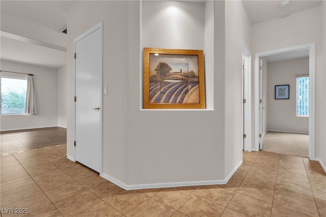 corridor with light tile patterned floors and baseboards