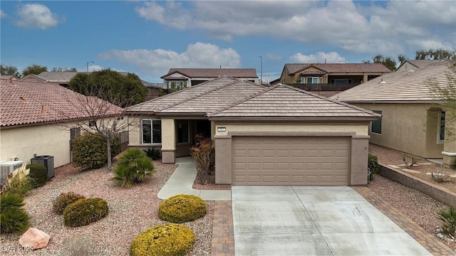 view of front of property featuring concrete driveway, central air condition unit, an attached garage, and stucco siding