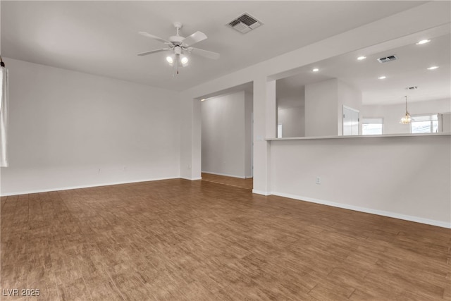 unfurnished room featuring visible vents, baseboards, wood finished floors, and ceiling fan with notable chandelier