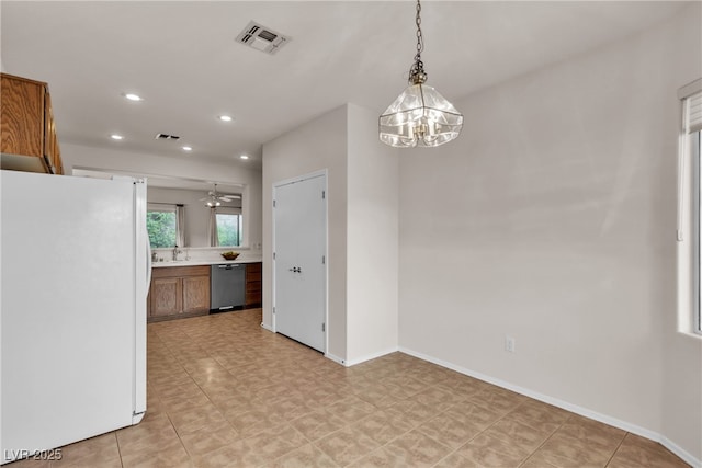 kitchen featuring visible vents, a sink, freestanding refrigerator, brown cabinetry, and dishwasher