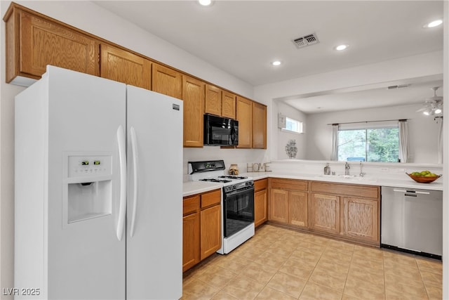 kitchen featuring range with gas cooktop, black microwave, white refrigerator with ice dispenser, stainless steel dishwasher, and a sink