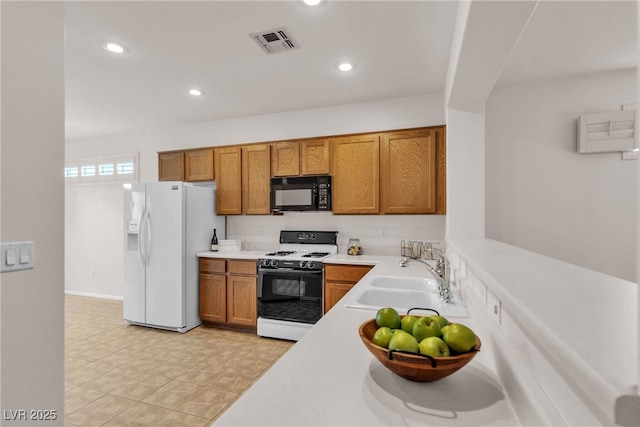 kitchen featuring visible vents, a sink, range with gas cooktop, white fridge with ice dispenser, and black microwave