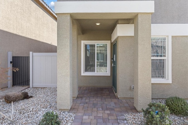 entrance to property with a patio area, fence, and stucco siding