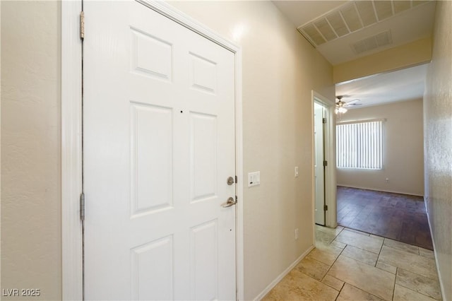 hall with light tile patterned floors, baseboards, and visible vents