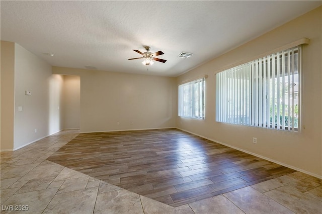 spare room featuring visible vents, a ceiling fan, a textured ceiling, wood finished floors, and baseboards