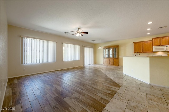 unfurnished living room with a ceiling fan, light wood-type flooring, visible vents, and recessed lighting