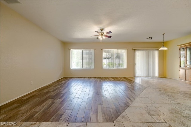 spare room featuring a ceiling fan, a healthy amount of sunlight, visible vents, and wood finished floors