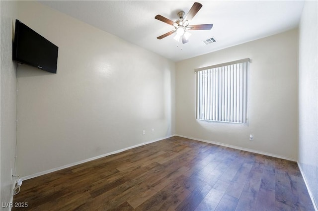 empty room with baseboards, dark wood-type flooring, visible vents, and a ceiling fan