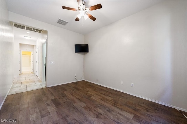 empty room with a ceiling fan, baseboards, visible vents, and wood finished floors