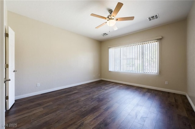 empty room featuring dark wood-type flooring, visible vents, baseboards, and a ceiling fan