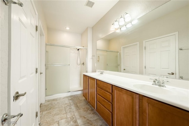 full bath featuring double vanity, a stall shower, a sink, and visible vents