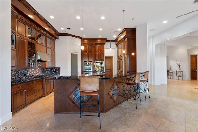 kitchen with built in appliances, range hood, tasteful backsplash, a kitchen bar, and glass insert cabinets