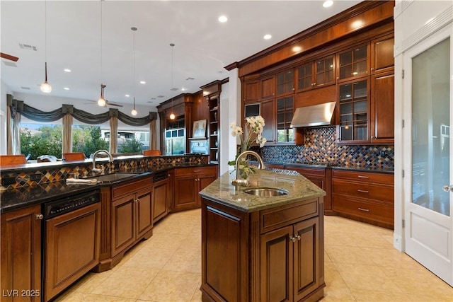 kitchen featuring a sink, backsplash, exhaust hood, and a center island with sink