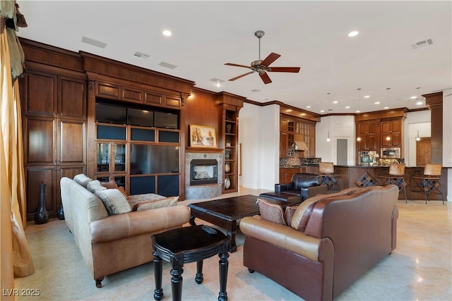 living area with a fireplace, recessed lighting, visible vents, ornamental molding, and ceiling fan