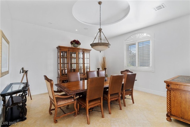 dining room with baseboards, visible vents, and a raised ceiling