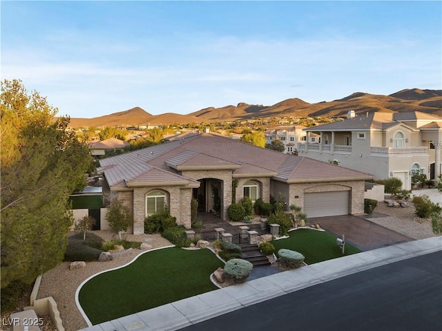 view of front of house with a garage, concrete driveway, a tile roof, and a mountain view