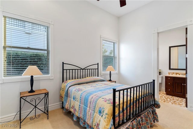 carpeted bedroom featuring ensuite bath, baseboards, and a ceiling fan