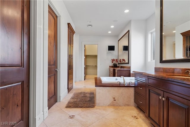 full bath with a closet, a bath, two vanities, tile patterned flooring, and a sink