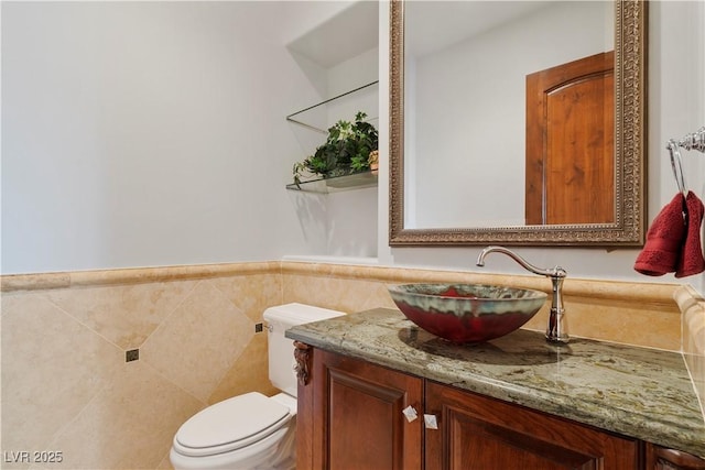 bathroom with wainscoting, tile walls, toilet, and vanity