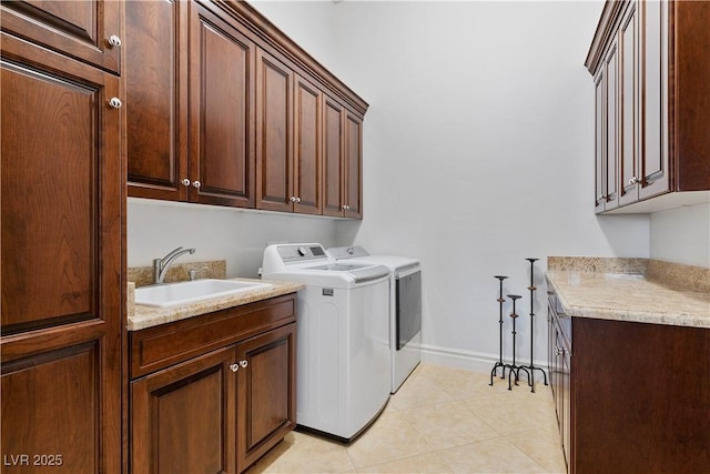 laundry room featuring light tile patterned floors, a sink, baseboards, cabinet space, and washer and clothes dryer