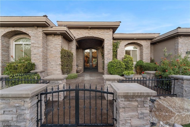 entrance to property with a gate, fence, and french doors