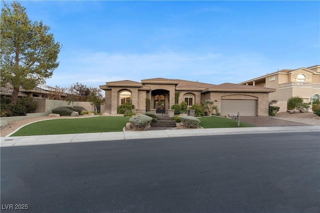 mediterranean / spanish house with driveway, an attached garage, fence, a front yard, and brick siding