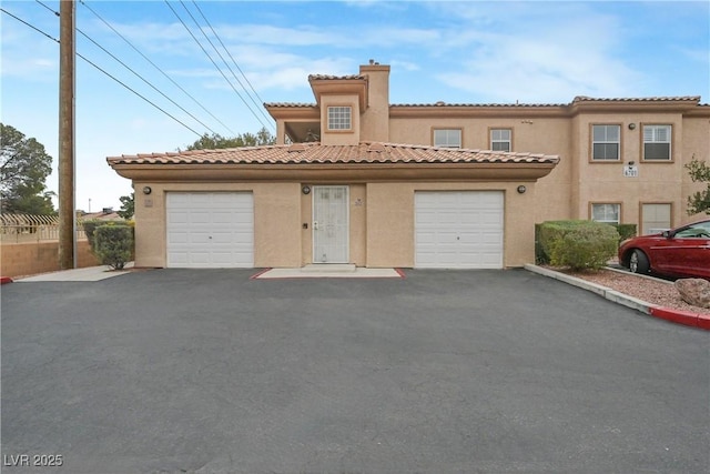 mediterranean / spanish house featuring a tiled roof, a chimney, and stucco siding