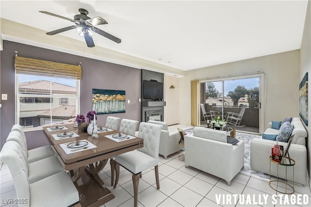 living room featuring a glass covered fireplace, ceiling fan, and light tile patterned flooring