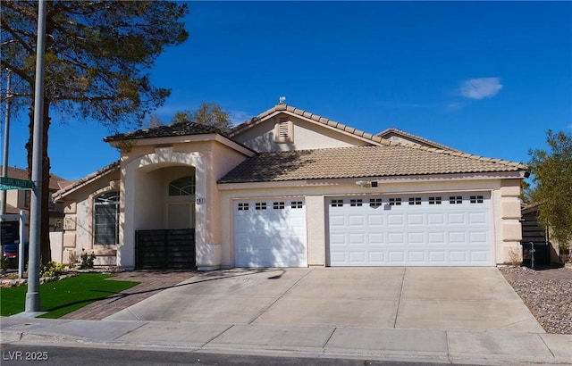 view of front of house with driveway, an attached garage, a tiled roof, and stucco siding