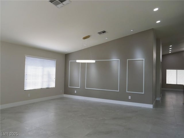 empty room featuring lofted ceiling, visible vents, and a healthy amount of sunlight