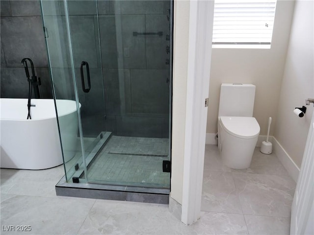 bathroom with a stall shower, a freestanding tub, toilet, and baseboards