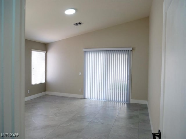 spare room featuring lofted ceiling, visible vents, and baseboards